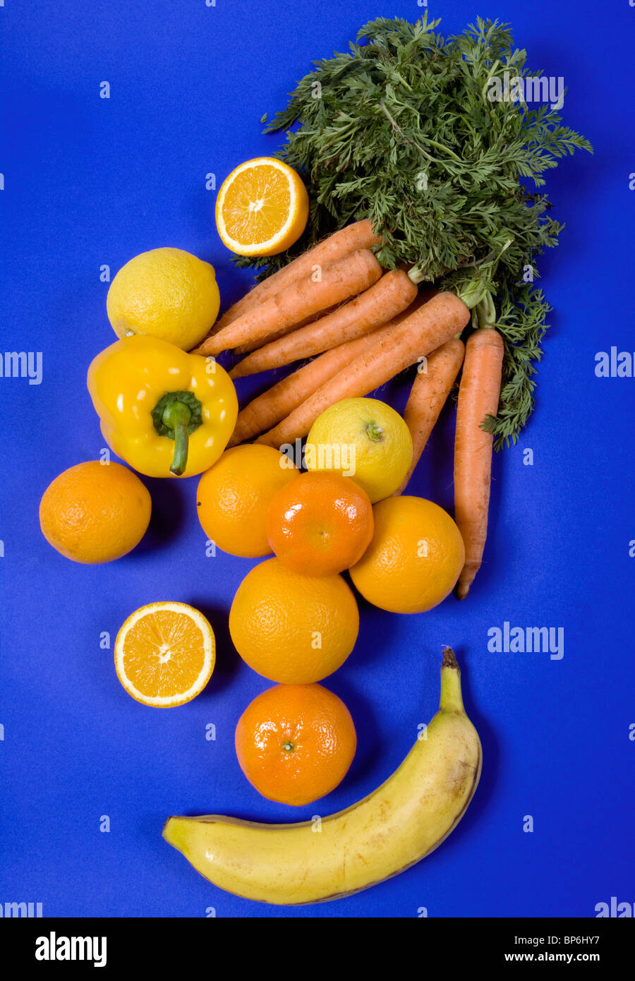 Arrangement of orange and yellow fruits and vegetables on a blue
