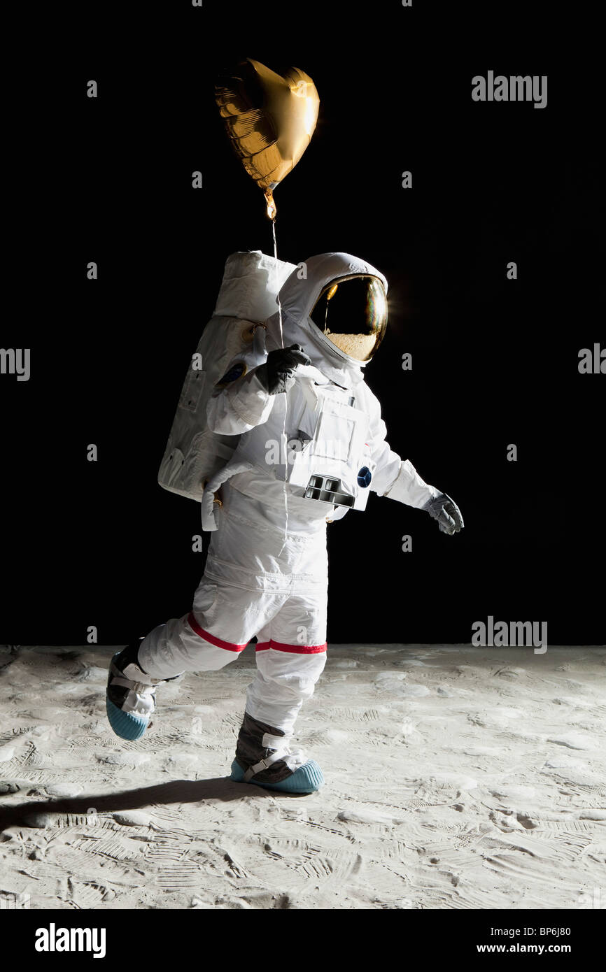 An astronaut on the moon holding a heart shaped helium balloon Stock Photo