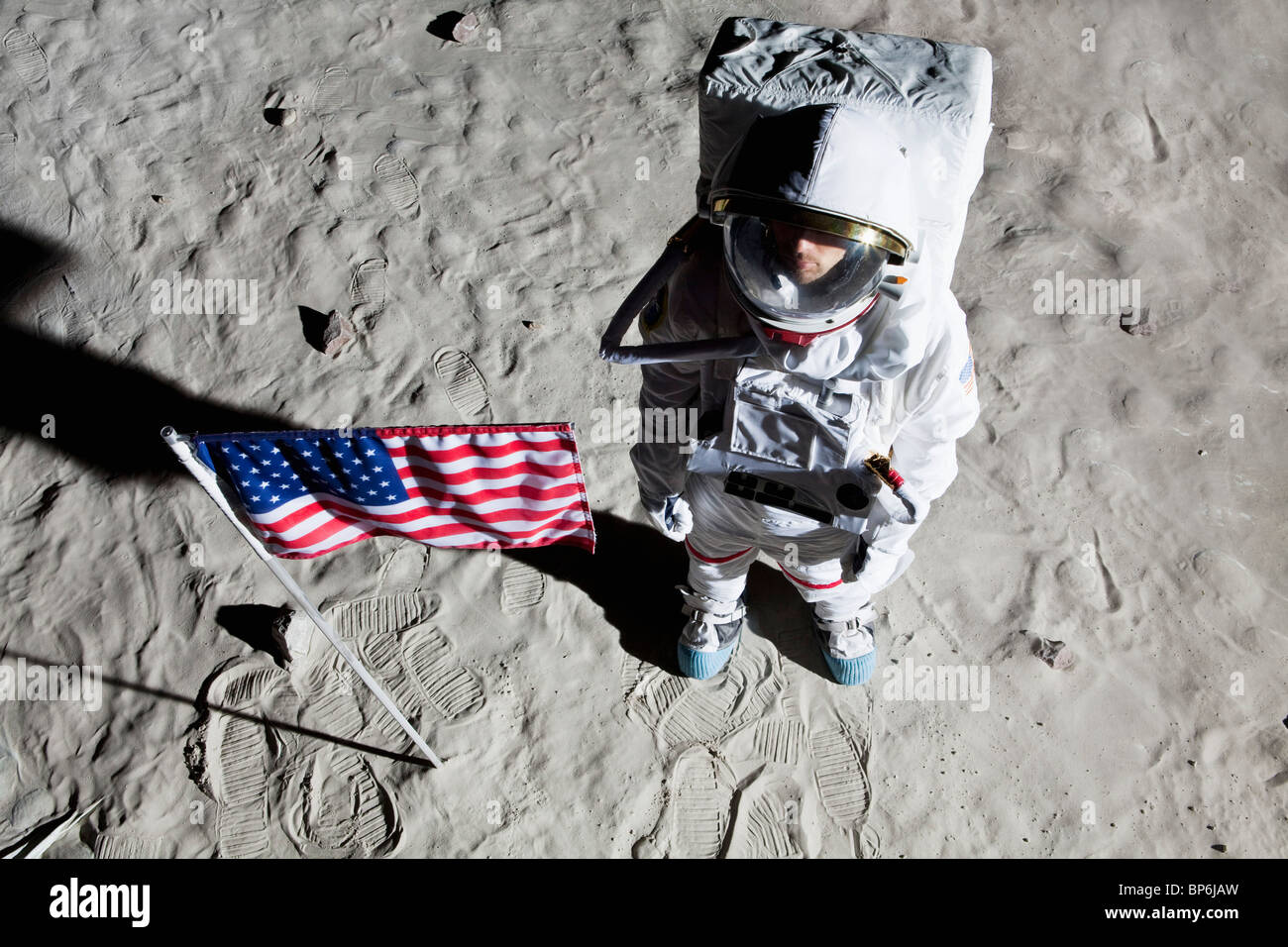 An astronaut on the surface of the moon next to an American flag Stock Photo
