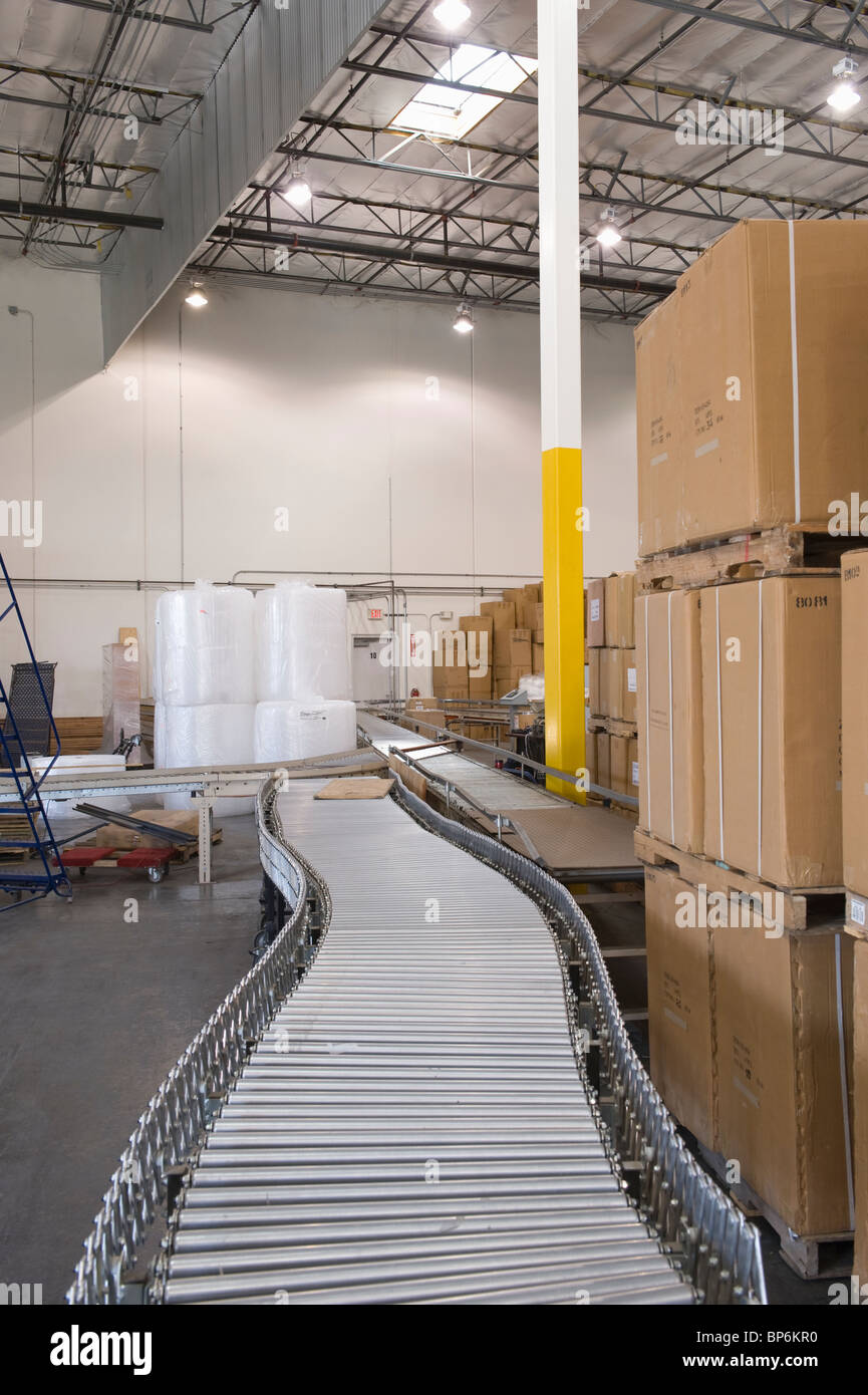 Cardboard boxes and conveyor belt in distribution warehouse Stock Photo