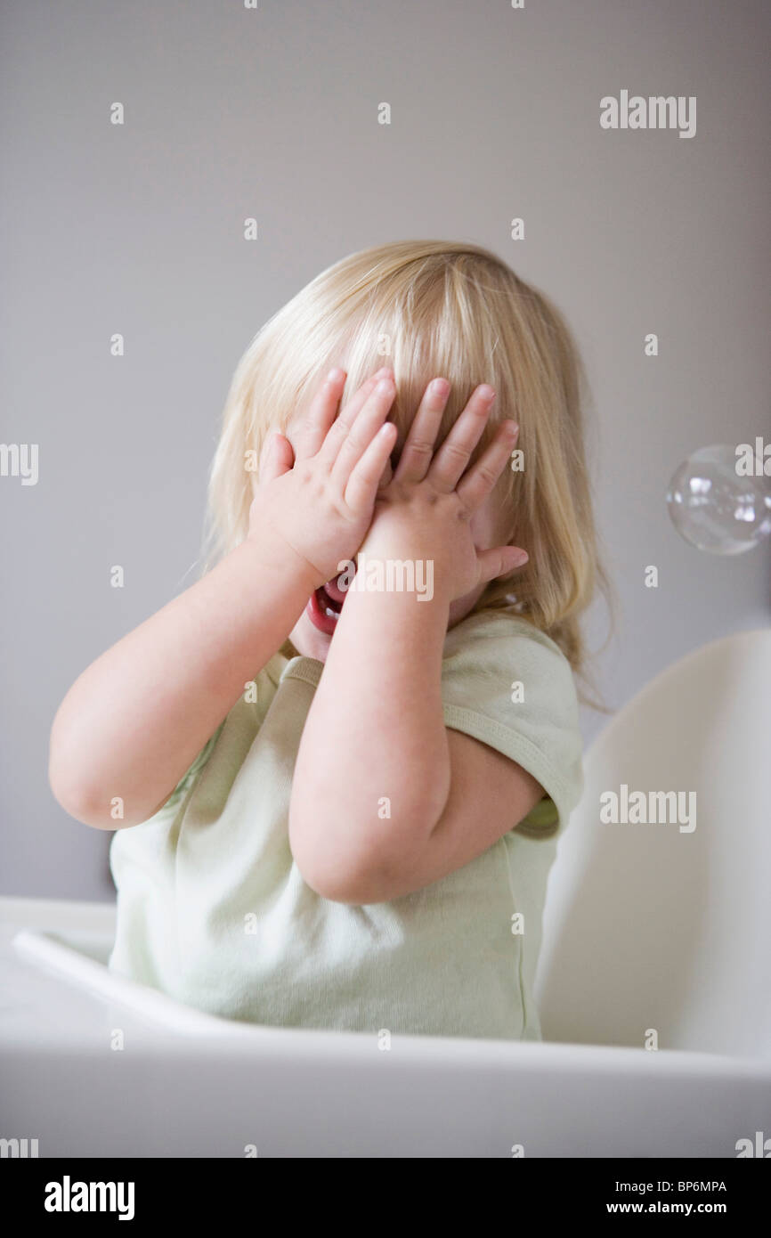 A young girl covering her face with her hands Stock Photo - Alamy