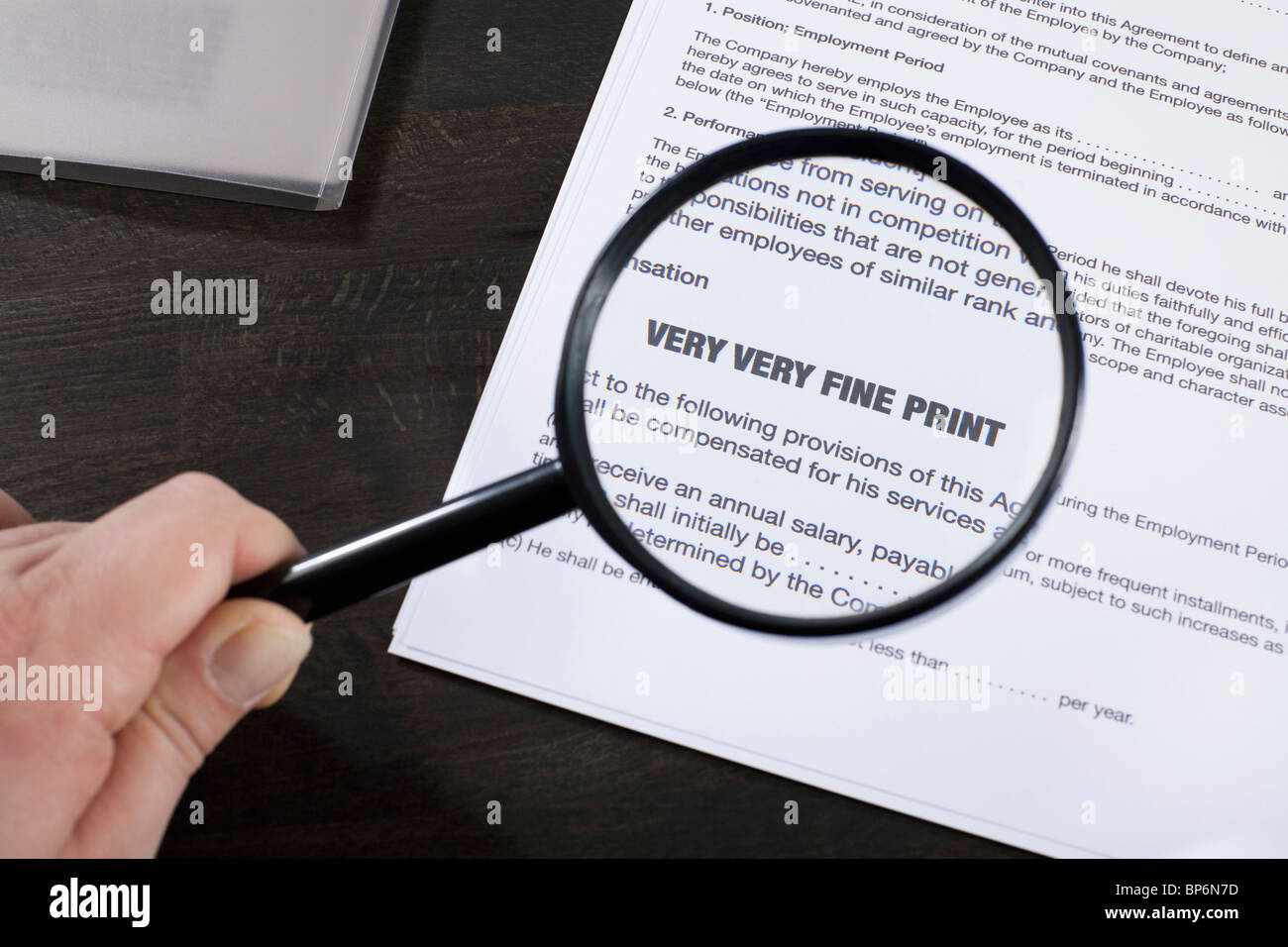 Examining the fine print of an employment agreement with a magnifying glass Stock Photo