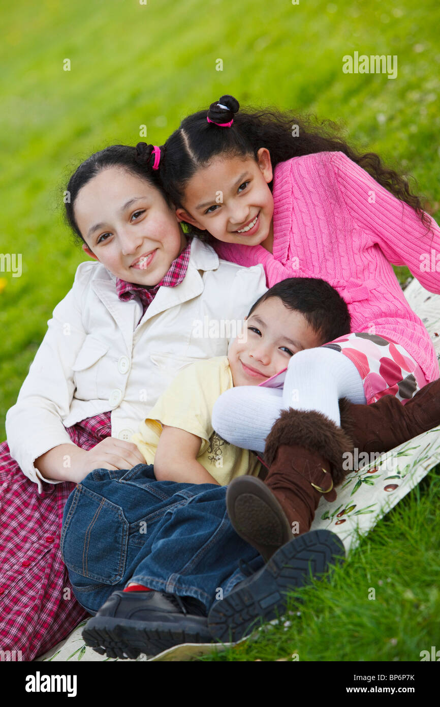 Portland, Oregon, United States Of America; A Boy And Two Girls Sitting On A Blanket On The Grass In Westmorland Park Stock Photo