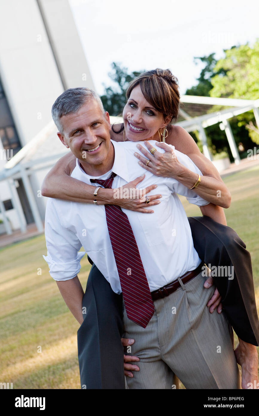 A businessman carrying a woman on his back Stock Photo