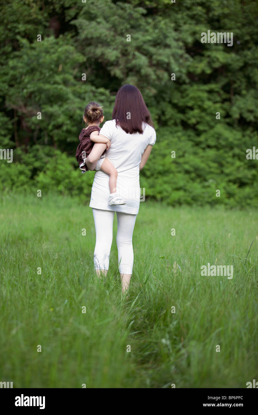 A woman holding her young daughter, rear view, outdoors Stock Photo