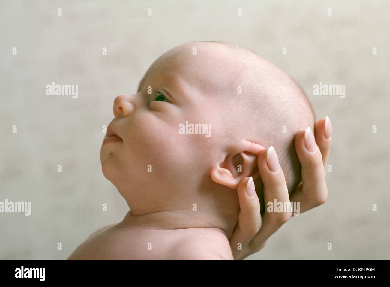 A mother's hand cradling her baby's head Stock Photo