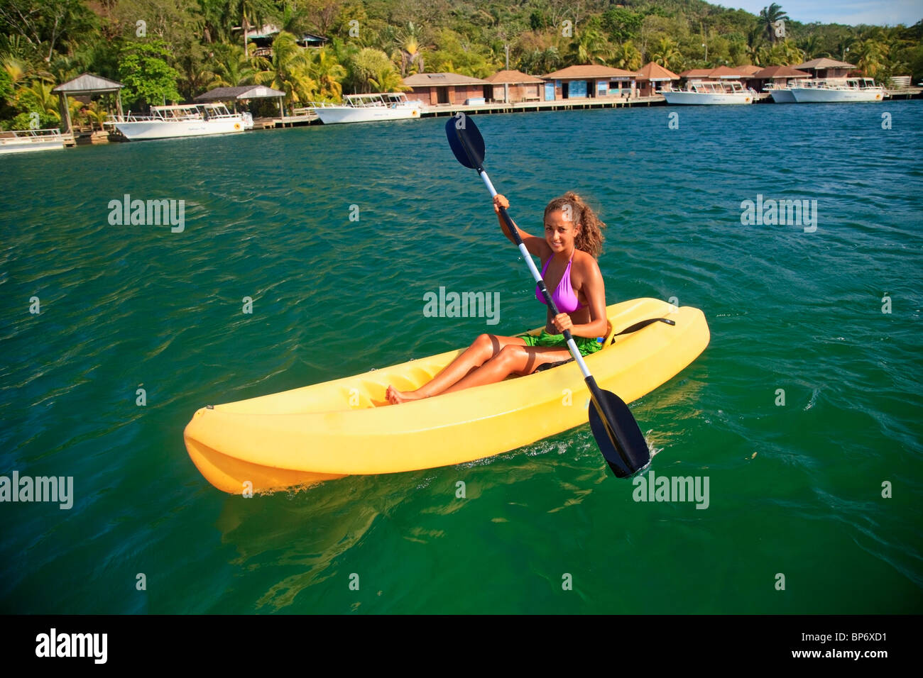 Roatan, Bay Islands, Honduras; A Young Woman Paddling A Kayak At ...