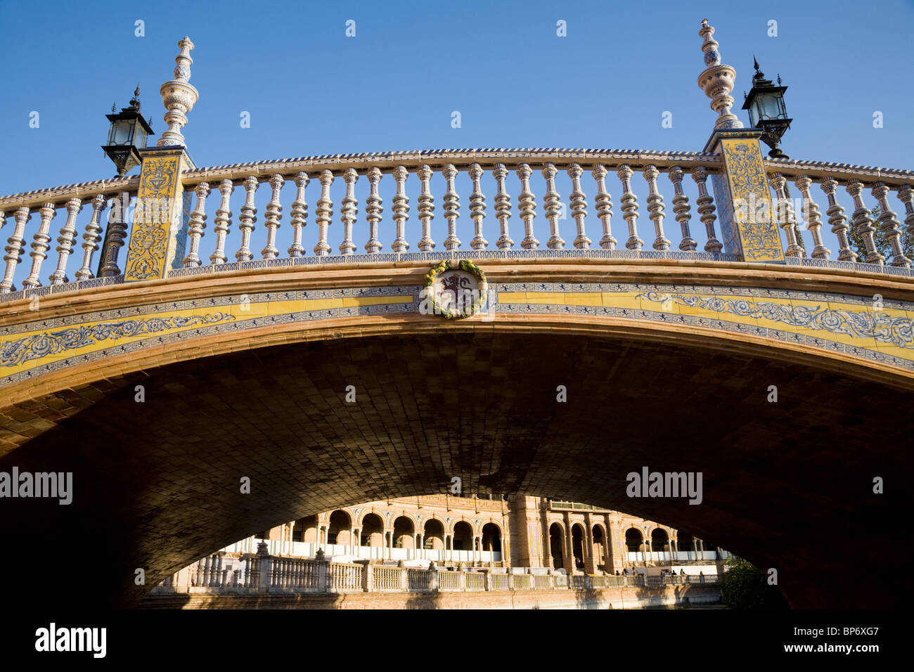 A bridge crossing / crosses over the moat of Seville's Plaza de España de Sevilla. Seville, Spain. On a sunny day with blue sky. Stock Photo