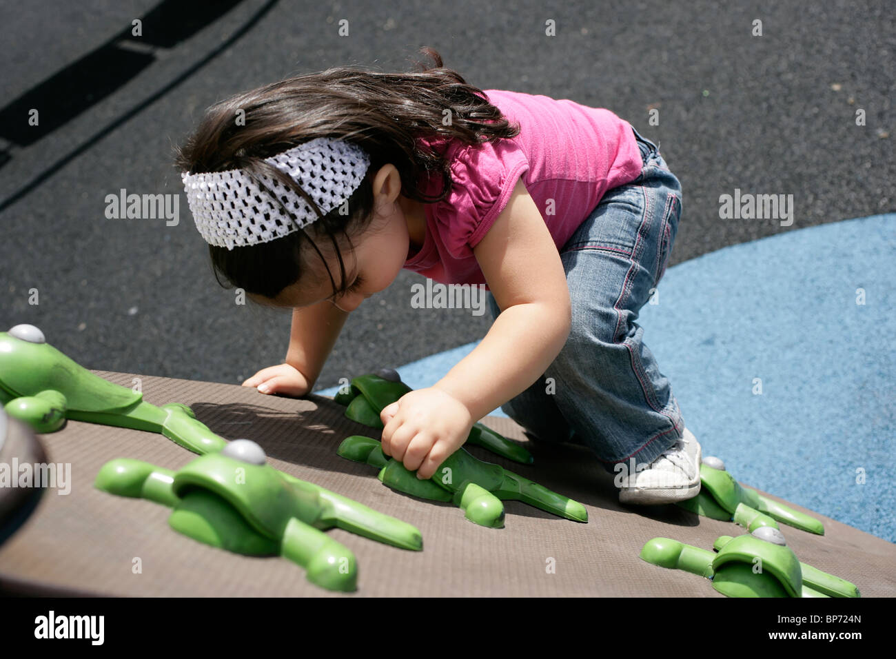 Two and a half year old toddler climbing in the playground Stock Photo