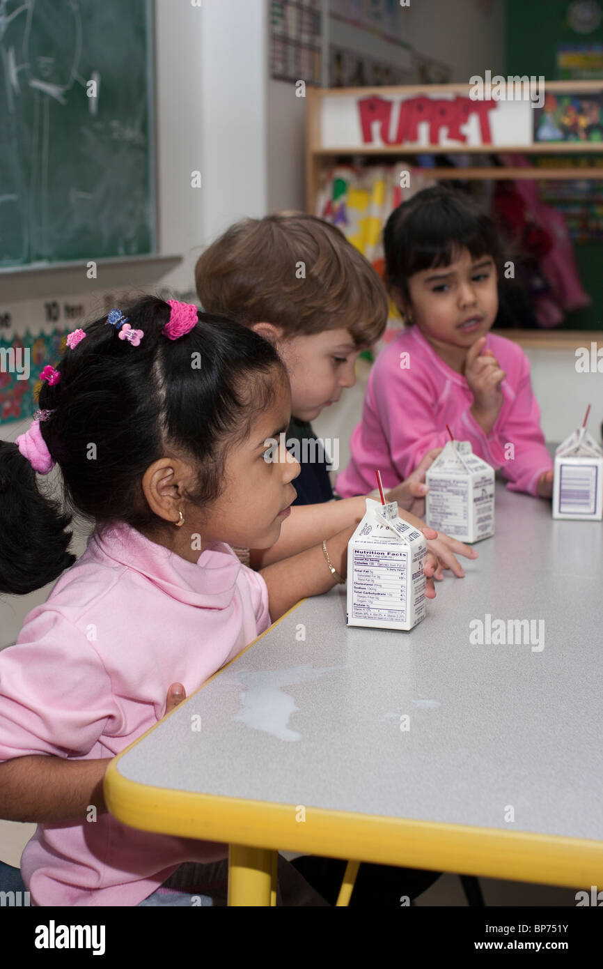 Three 4 year old preschool children eating lunch in the classroom Stock