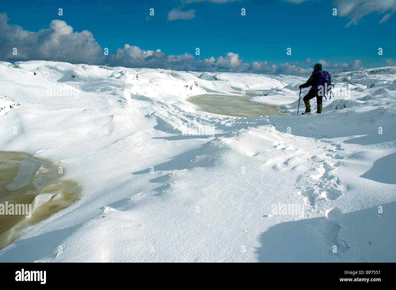 A walker on the frozen Kinder Scout plateau in winter, near Hayfield, Peak District, Derbyshire, England, UK Stock Photo