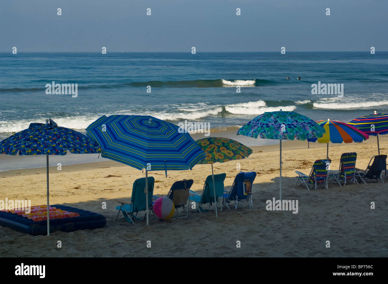 Empty chairs and shade umbrellas lined up in a row in early morning on Carlsbad State Beach, Carlsbad, San Diego, California Stock Photo