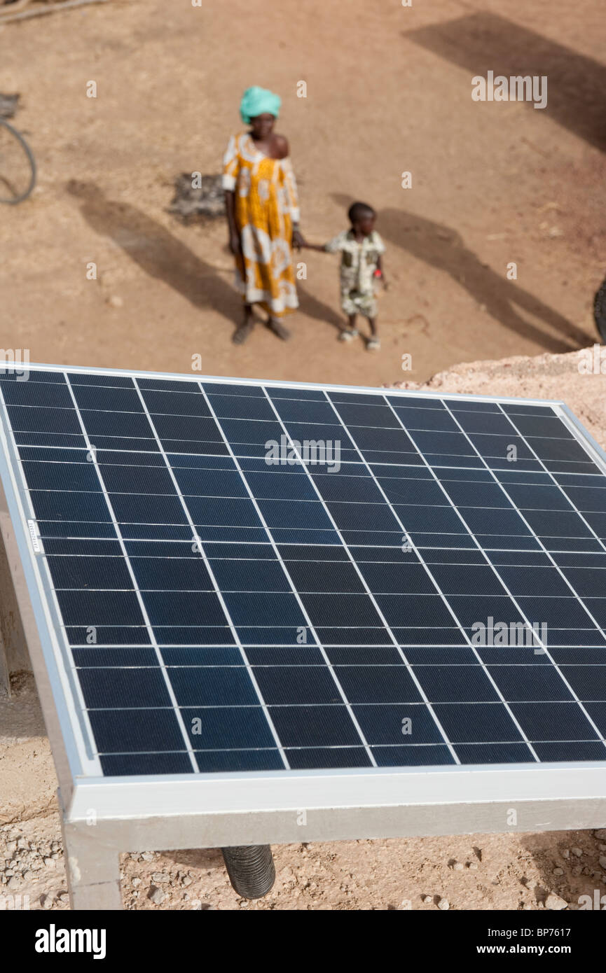West Africa Mali , solar panel on rooftop of solar powered battery recharge station in village Dialkoro , woman with child Stock Photo