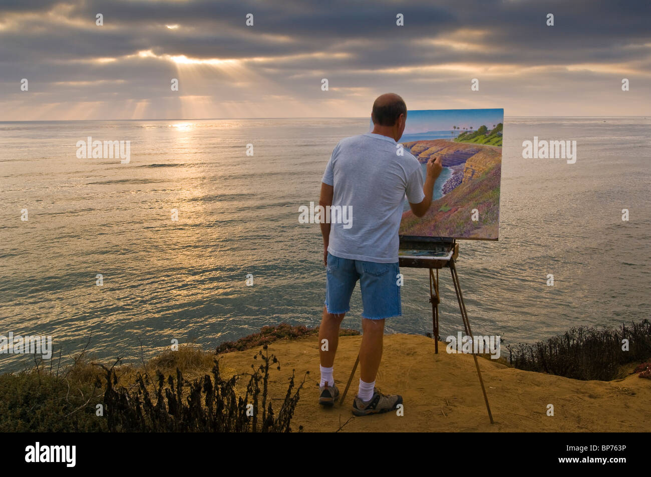 Artist Bill Jewell plein aire painting on coastal bluff overlooking the ocean at Sunset Cliffs, San Diego, California  Stock Photo