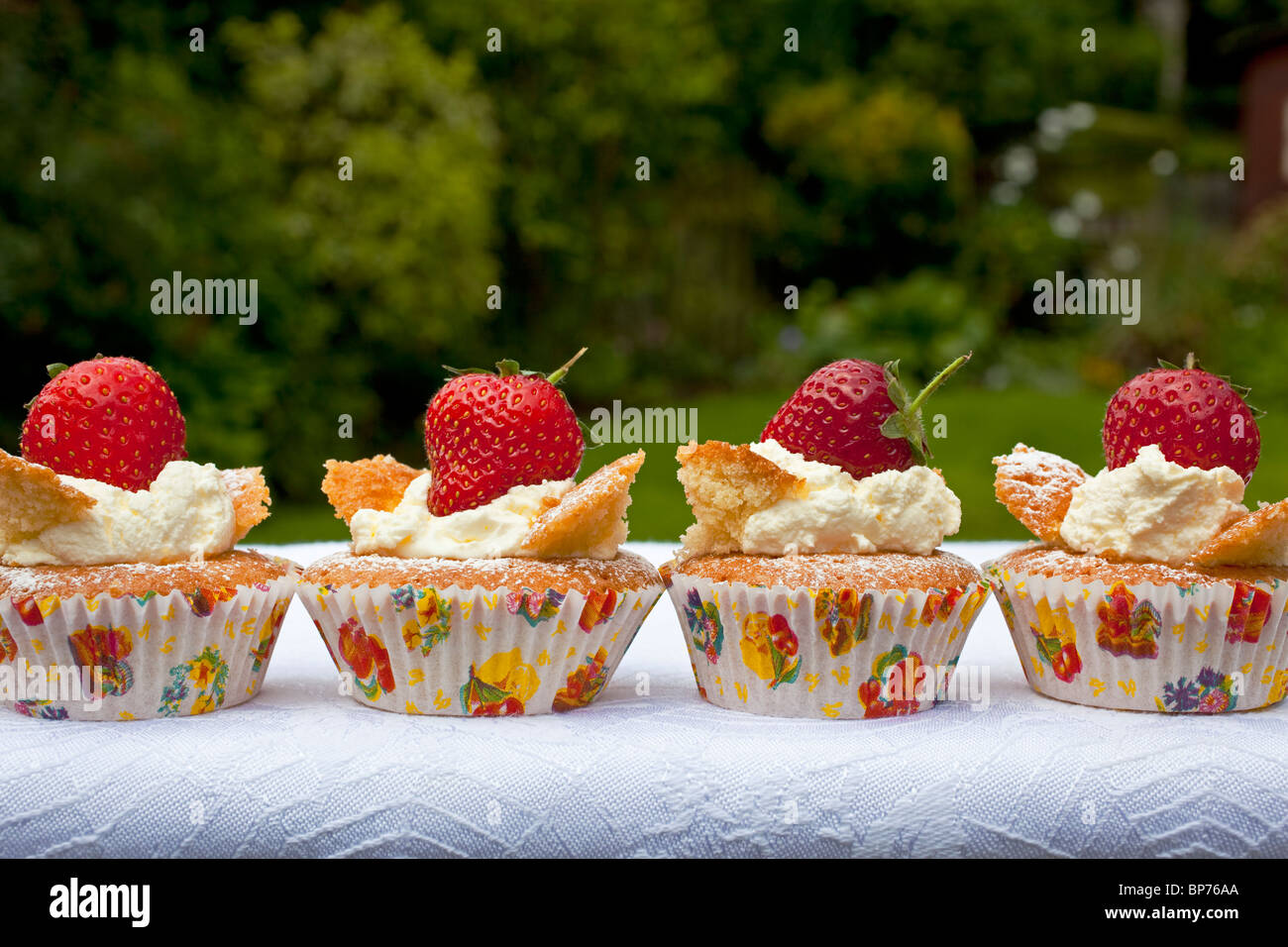 Four fresh cream strawberry buns in a garden setting Stock Photo