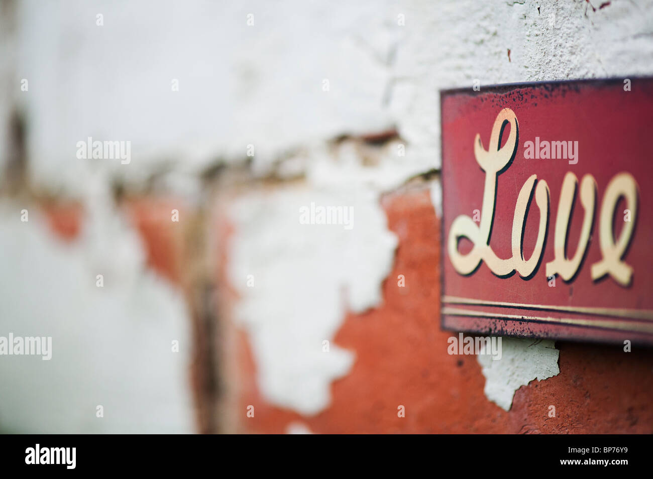 Love. Old metal garden sign on a painted brick wall Stock Photo