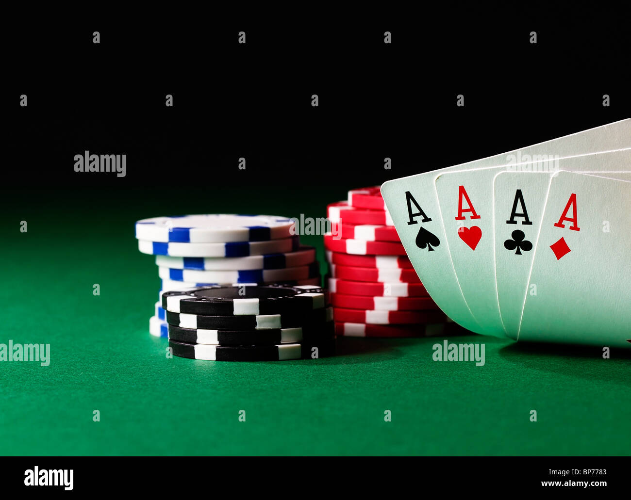 four aces high on green table with chips on black background Stock Photo