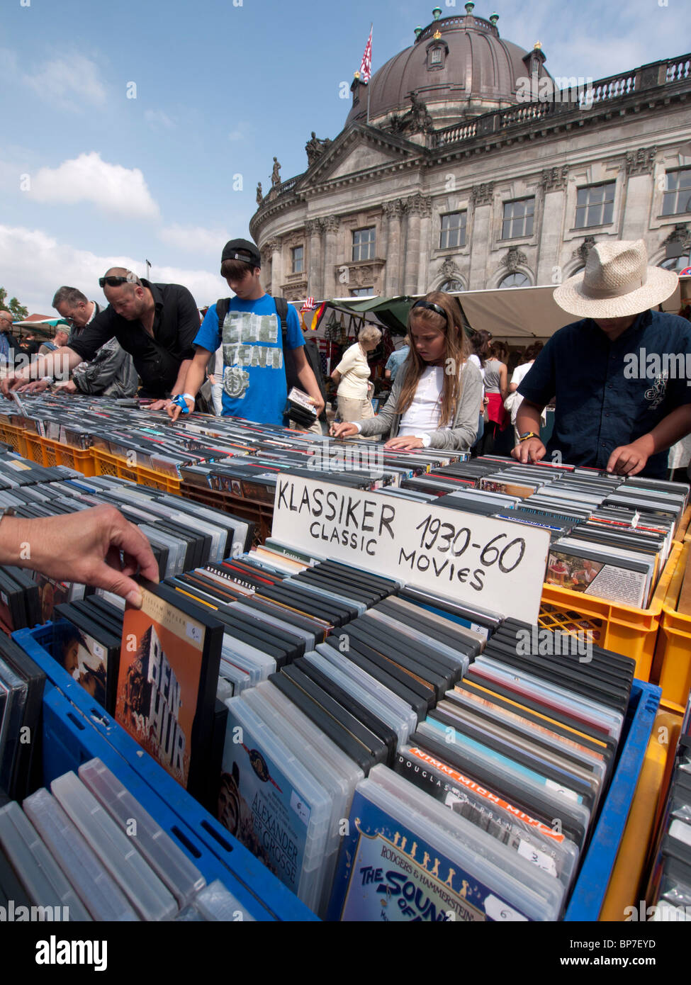 People browsing second hand movies at outdoor weekend fleamarket beside