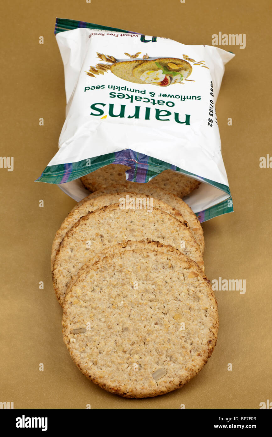 Small 86 gram packet of Nairns sunflower and pumpkin seed oatcakes spilling onto a gold surface Stock Photo