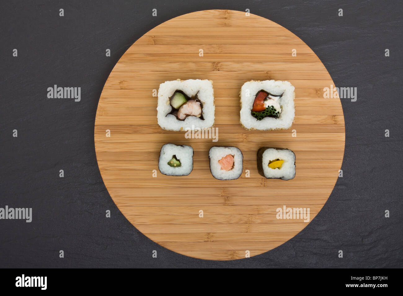 Sushi and bamboo board on dark grey slate background. Stock Photo