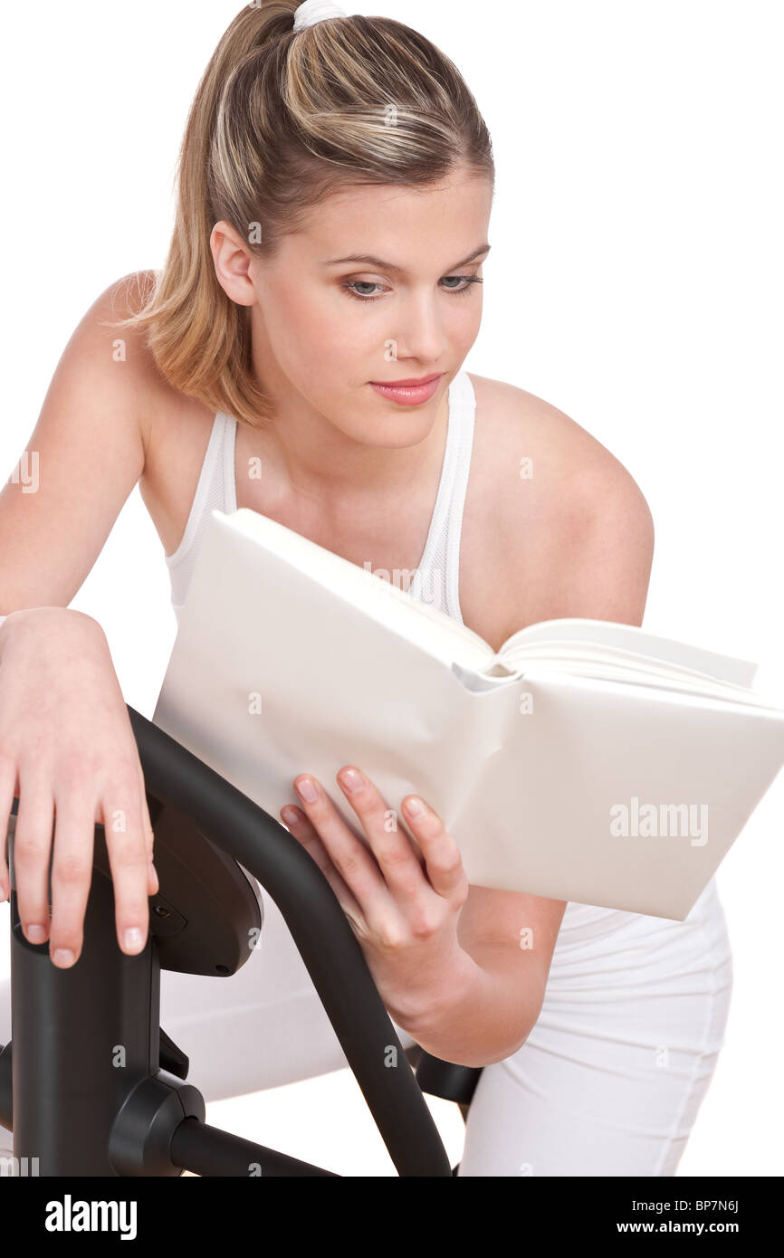 Fitness series Woman reading book cycling on exercise bike Stock
