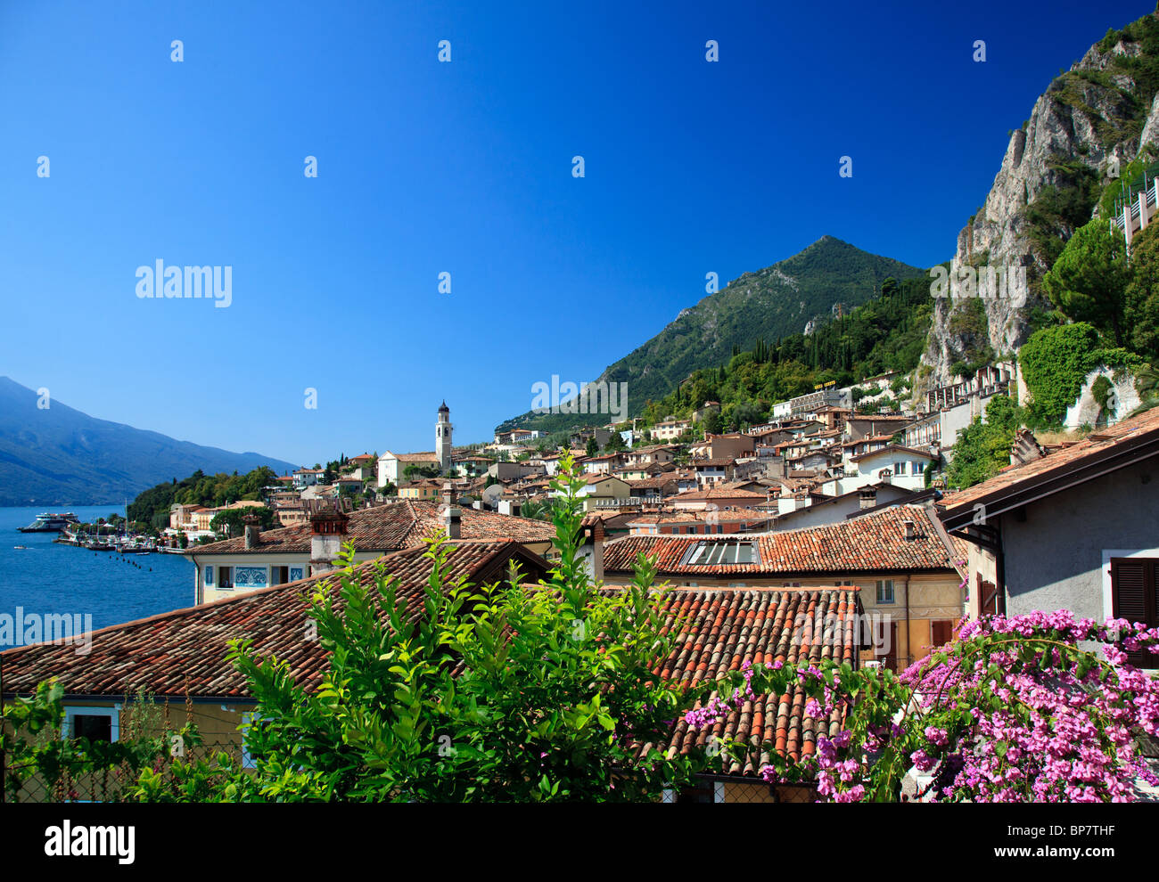 View over Lake Garda, Italy with flowers framing the rooftops of Lake Garda town of Limone in Lake Garda, Lombardy, Italy Stock Photo