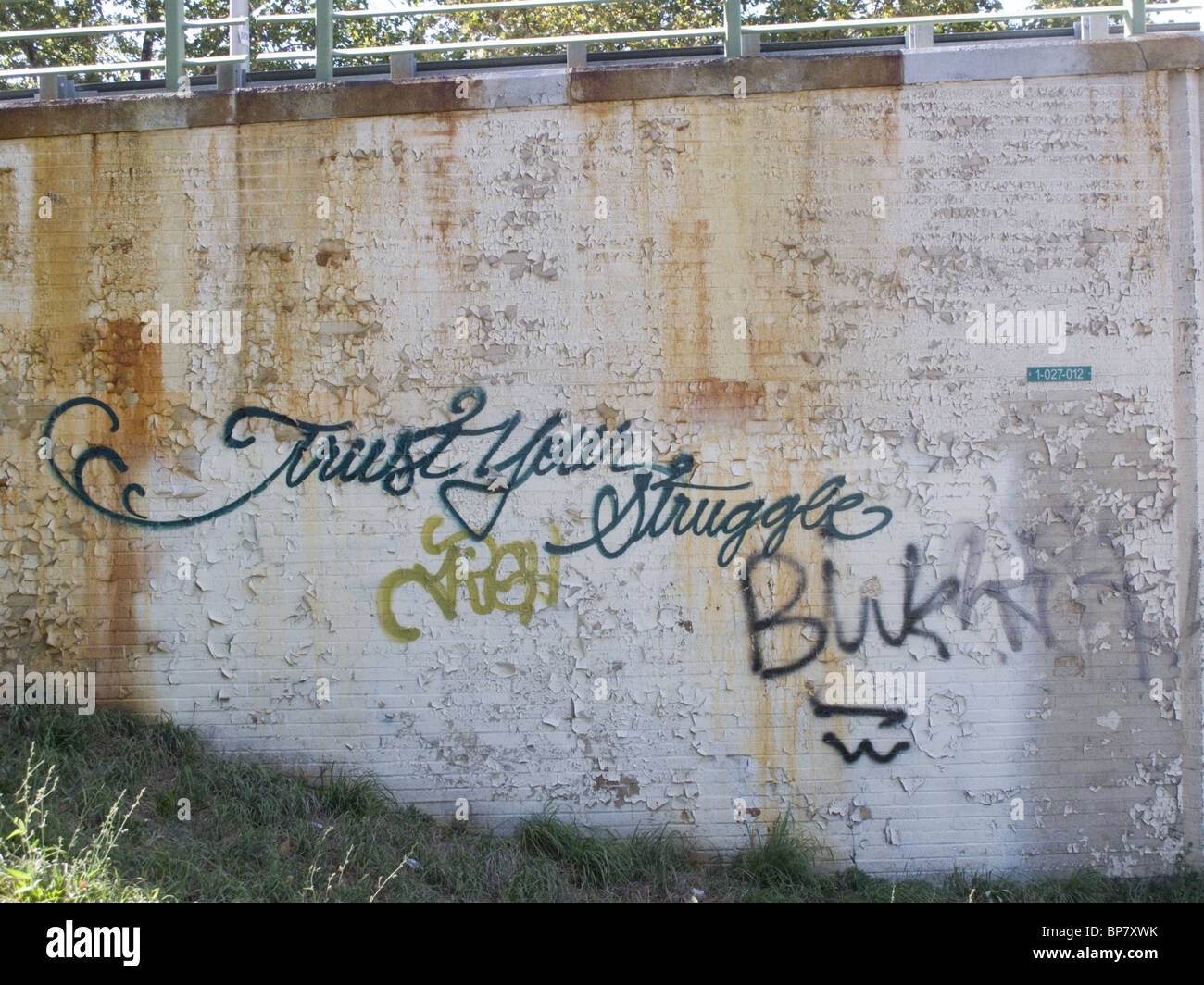 'Trust in your struggle' written on a retaining wall near a subway entrance in Brooklyn, NY Stock Photo