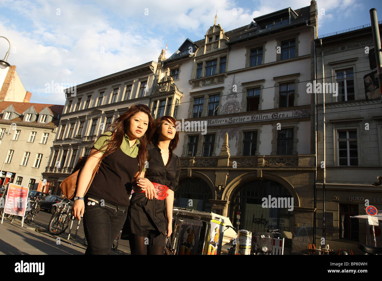 Two Asian women walking past a cafe in Berlin, Germany Stock Photo