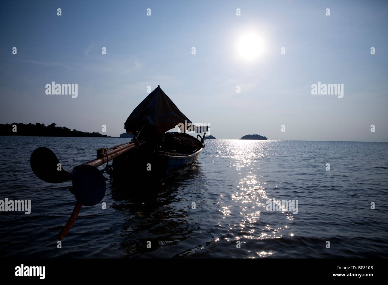Longtail boat floats, anchored, on the water in the afternoon sun . Koh Chang, Thailand Stock Photo