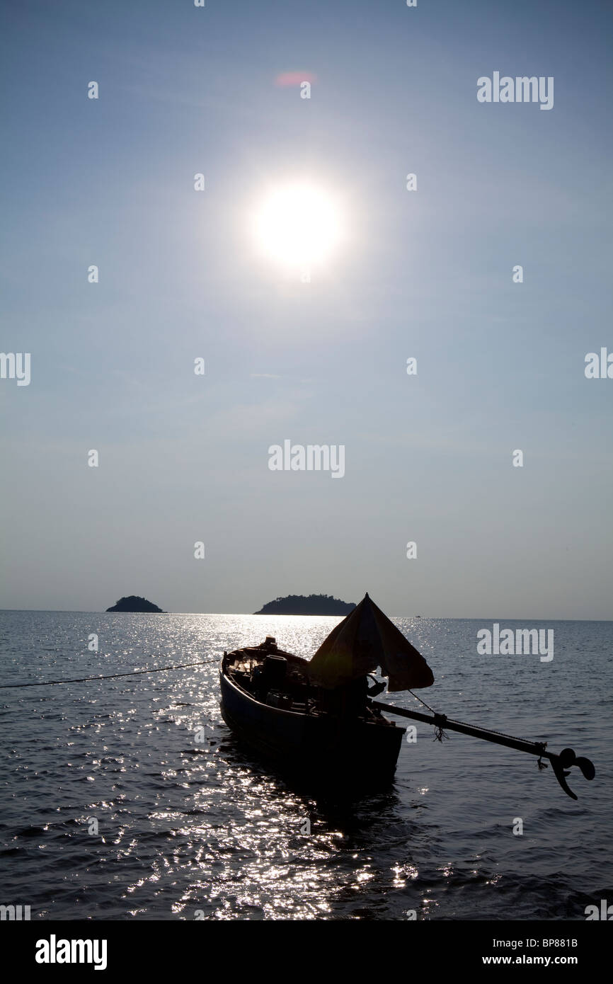 Longtail boat floats, anchored, on the water in the afternoon sun . Koh Chang, Thailand Stock Photo