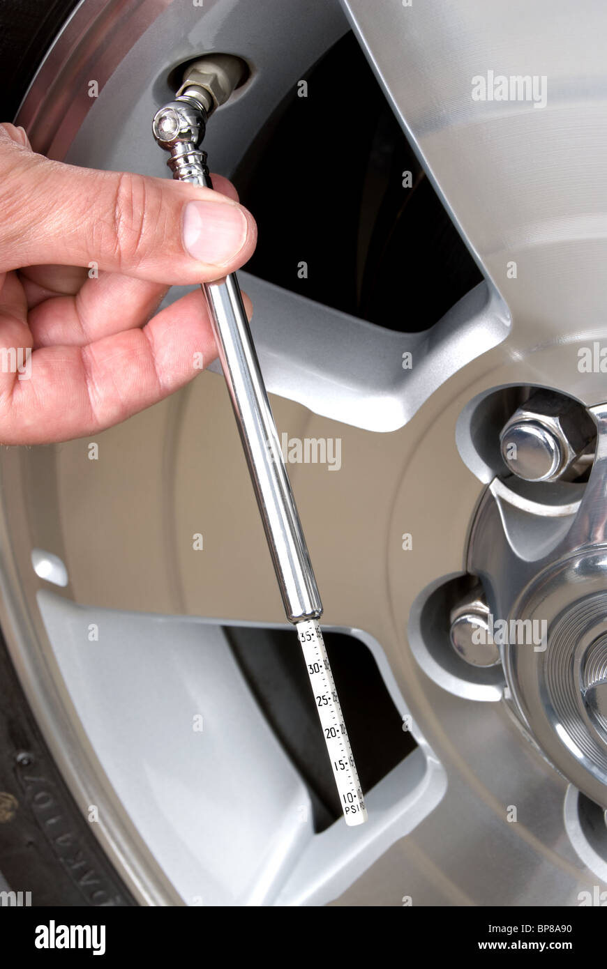 Person checks their tire pressure with a tire gage. This is a good image for responsible car maintenance inferences. Stock Photo
