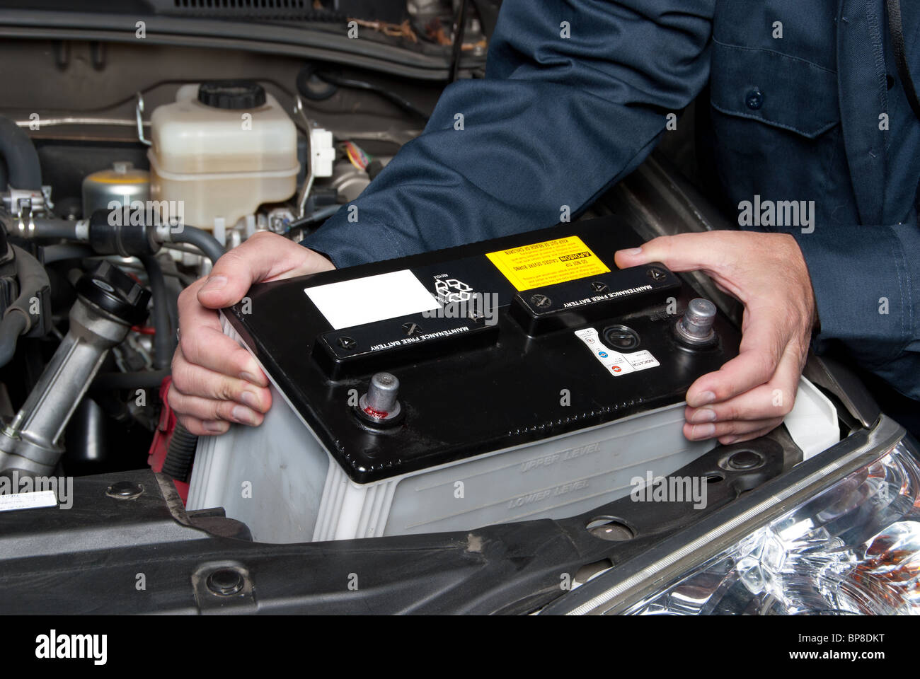 A car mechanic replaces a battery. Stock Photo