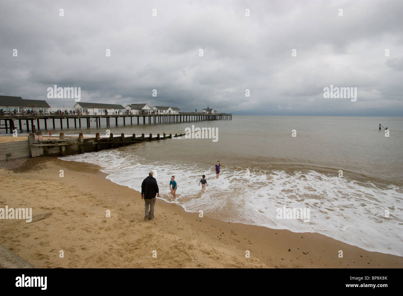 Southwold Beach, Suffolk, UK with bathers enjoying the sunshine in background the iconic Southwold Pier stretch's into the sea Stock Photo