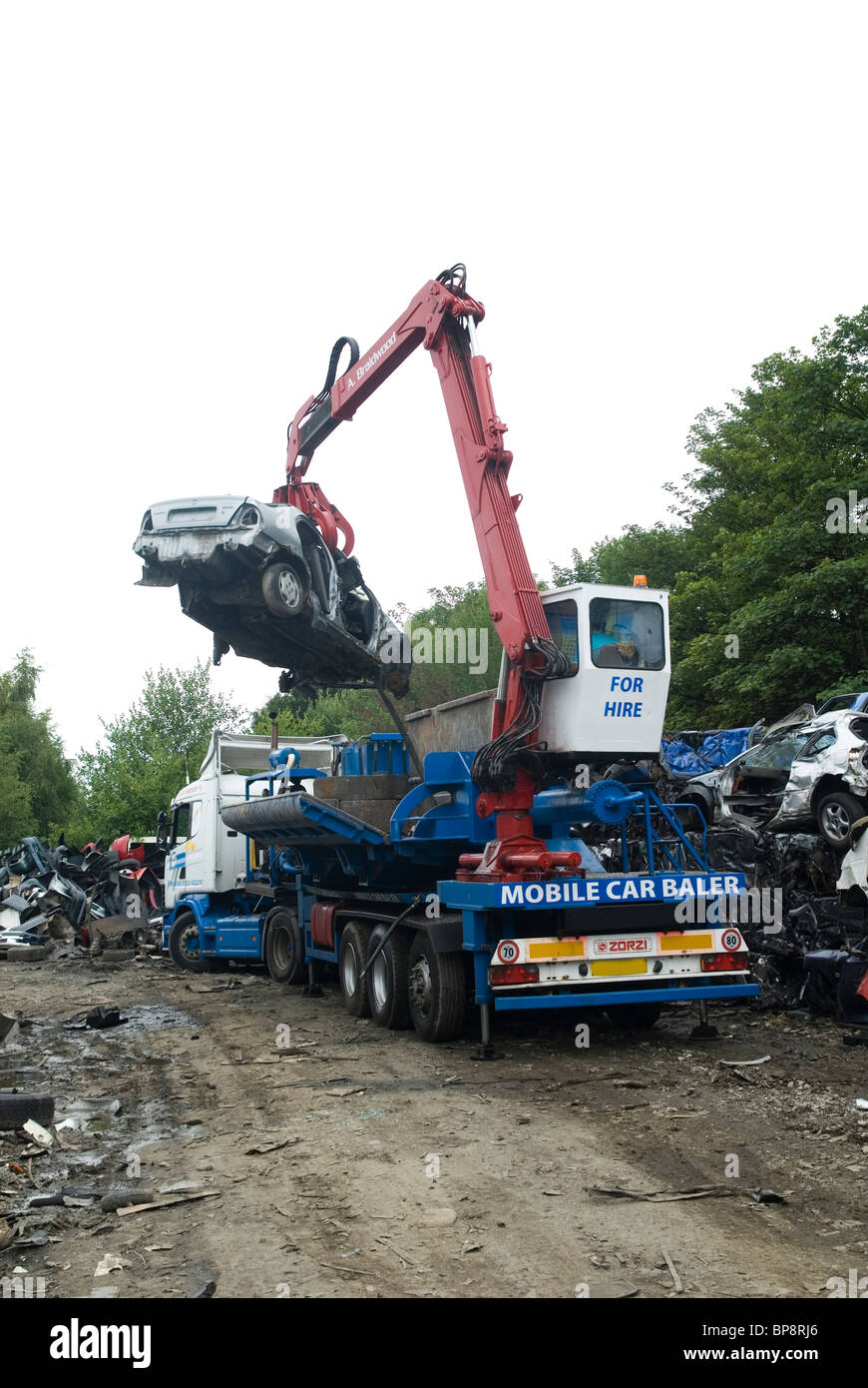 Man working on a grab crane in a cars recycling scrapyard UK Stock Photo