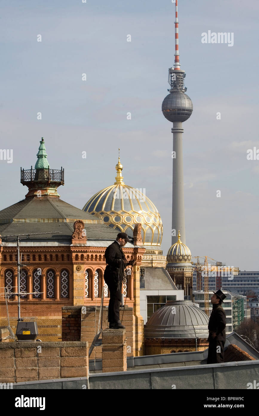 Chimney sweeps standing on roof, dome of New Synagogue, in background, Berlin, Germany Stock Photo
