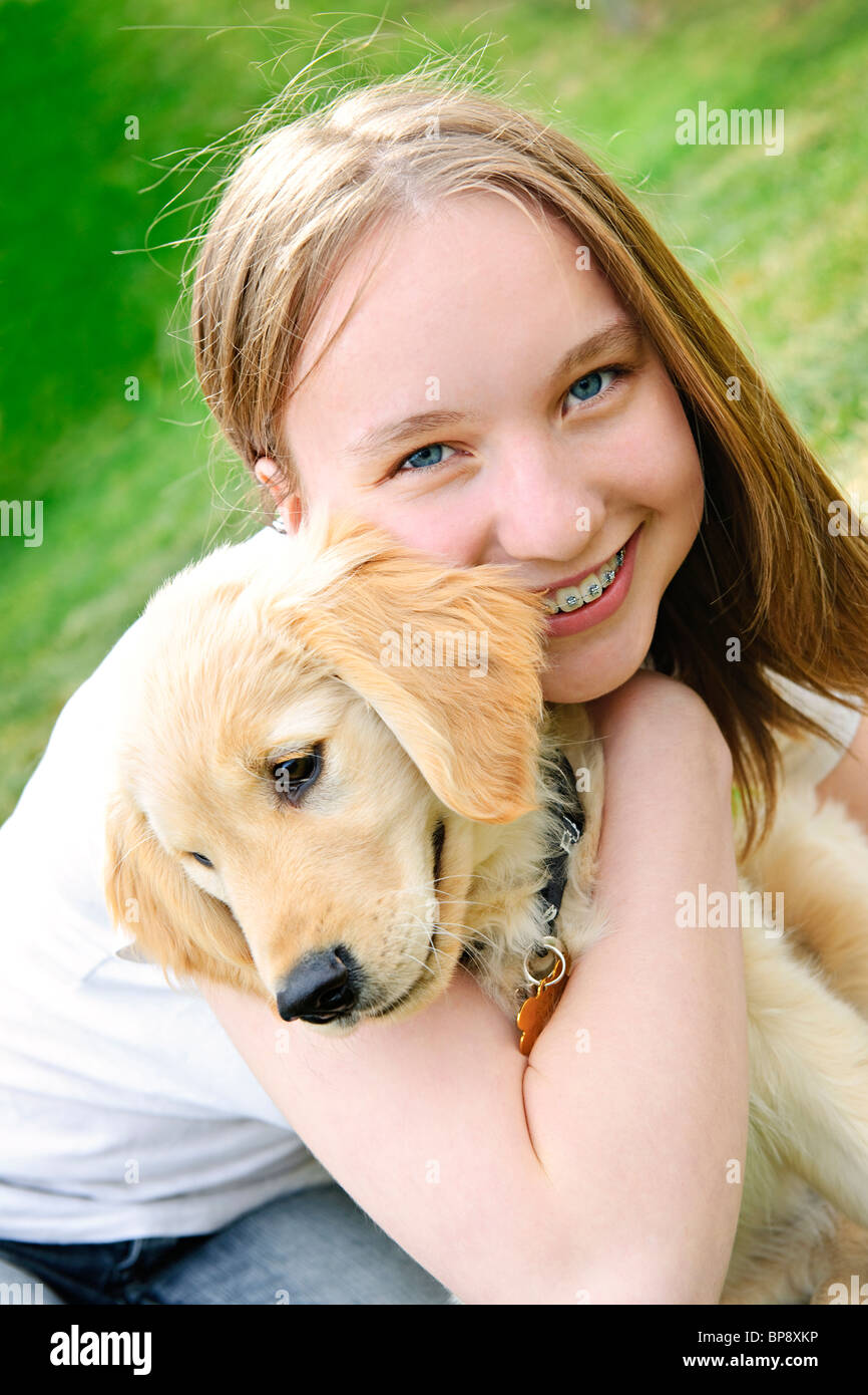 Portrait of smiling teenage girl holding golden retriever puppy Stock Photo