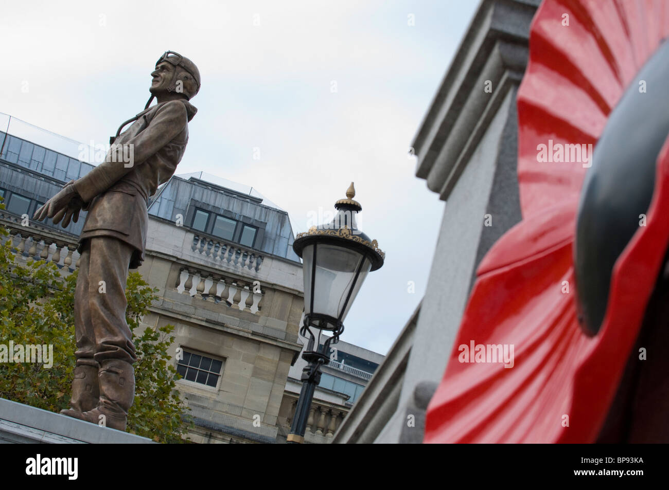 A statue of Air Vice Marshal Sir Keith Park looks out as serving soldiers sell poppies in Trafalgar Square Stock Photo