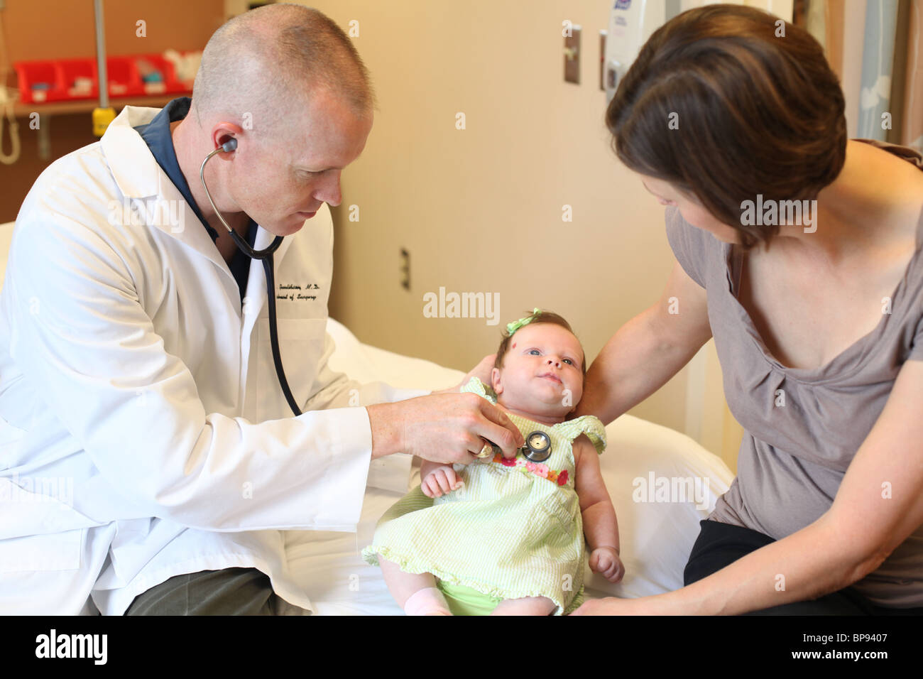 male doctor giving infant child a check up with mother at doctor's office Stock Photo