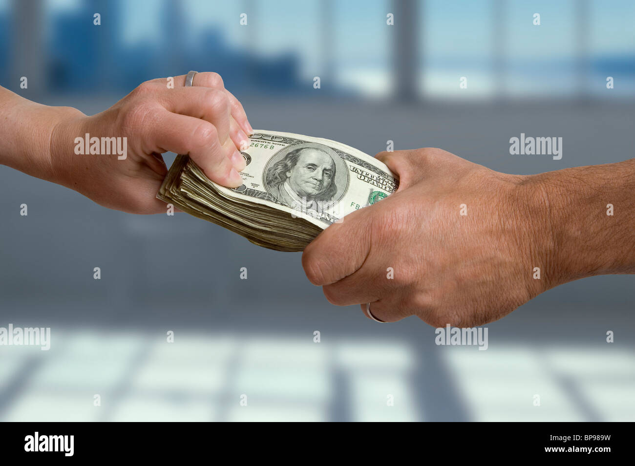 A man's and woman's hand each grasping at a stack of cash. Stock Photo