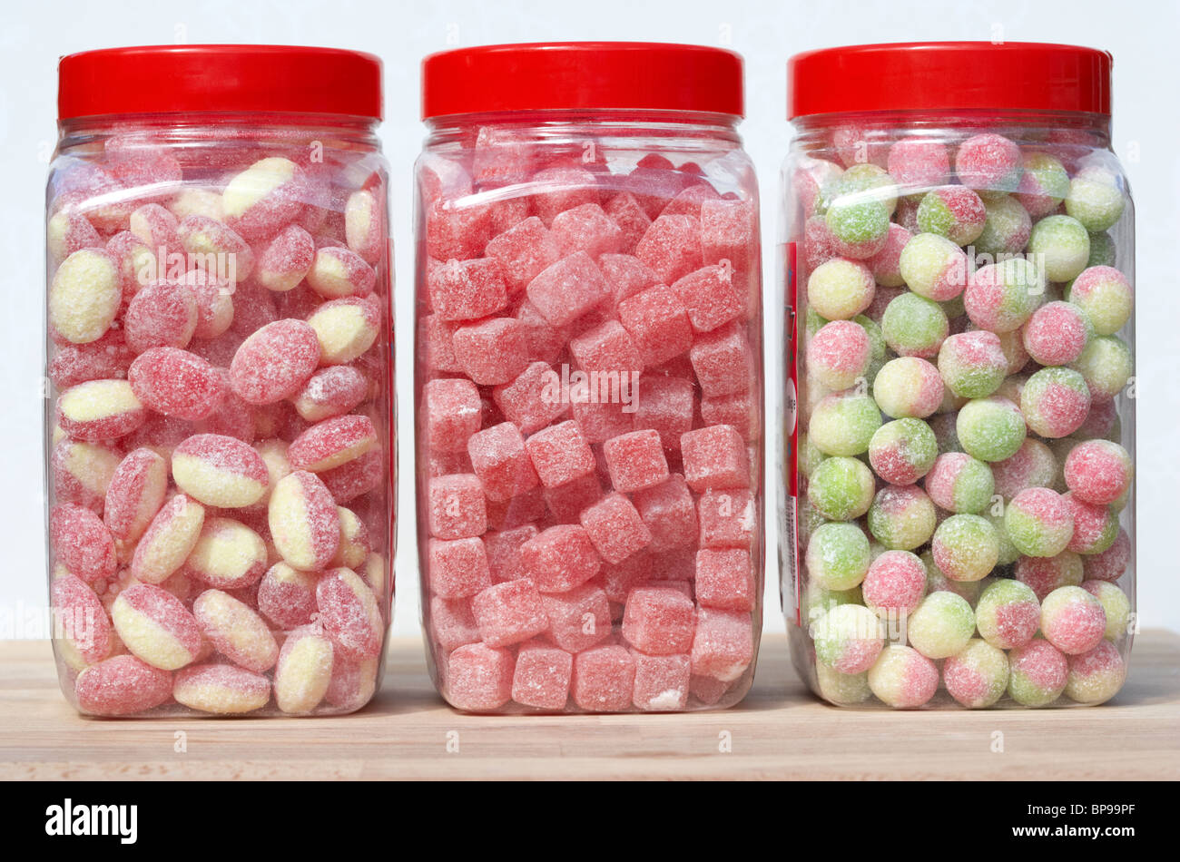 jars containers of traditional british sweets candies including rhubarb and custard cola cubes and rosey apples in the uk Stock Photo