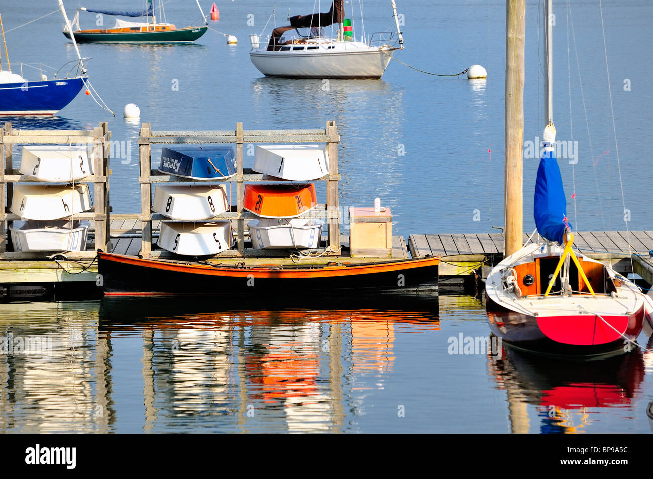 Tranquil scene of Rockland Harbor Maine with colorful boats moored to pier dock quay and colourful reflections in water. Stock Photo