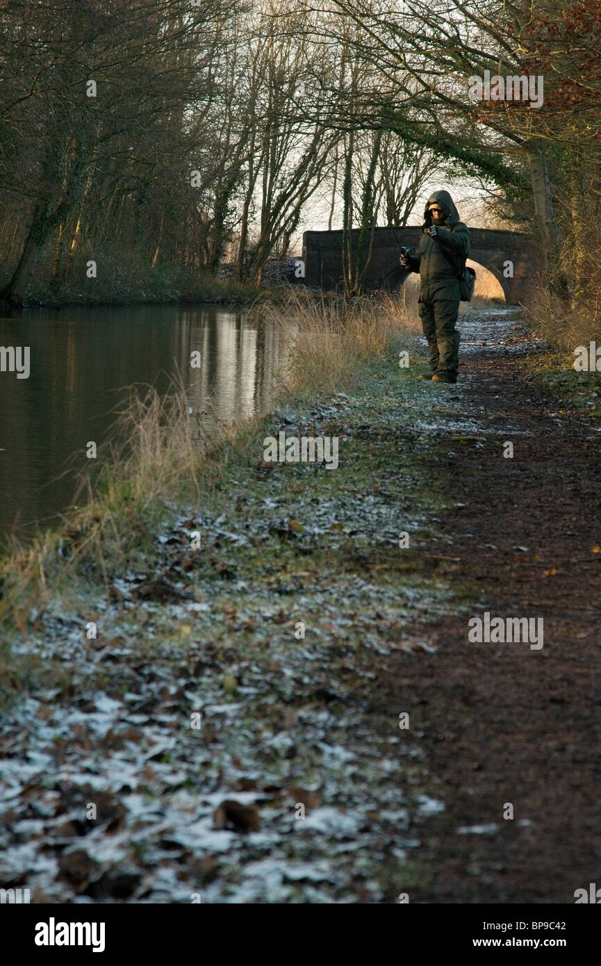 A lone angler fishing from frozen canal towpath. Stock Photo