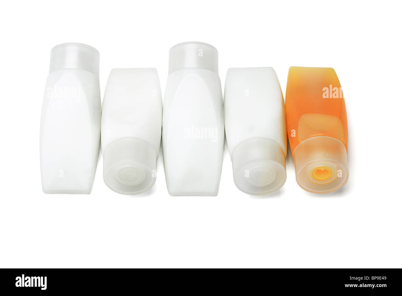 Lone tube of orange shampoo among containers of shower gel on white