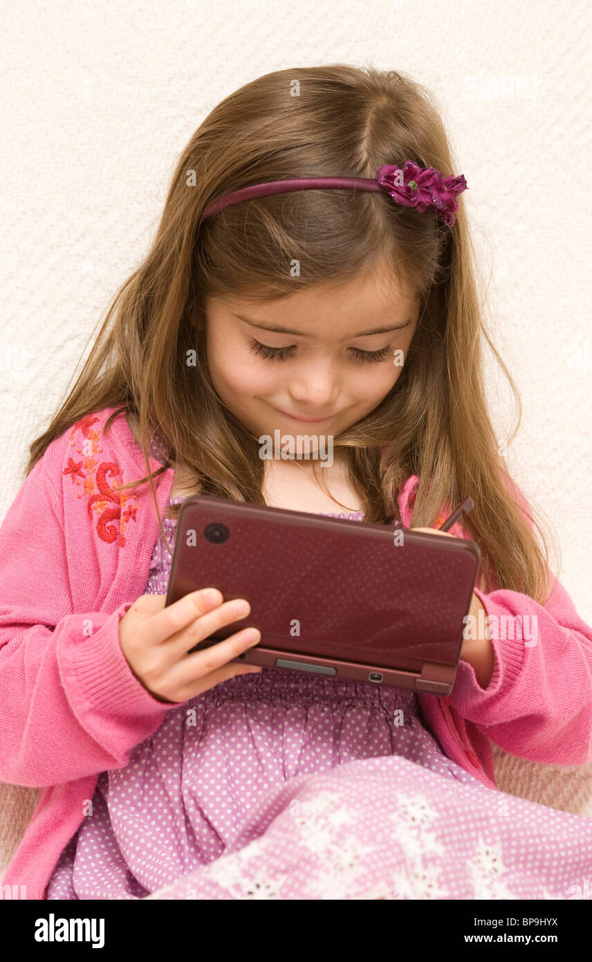 A young girl plays on a Nintendo DS Lite. Picture by James Boardman Stock Photo