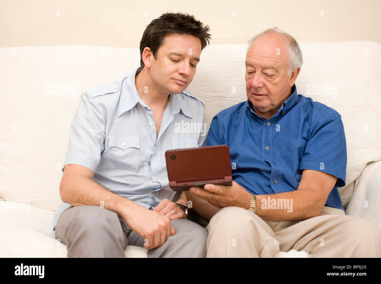 A young man plays on a Nintendo DS Lite with his father. Picture by James Boardman Stock Photo