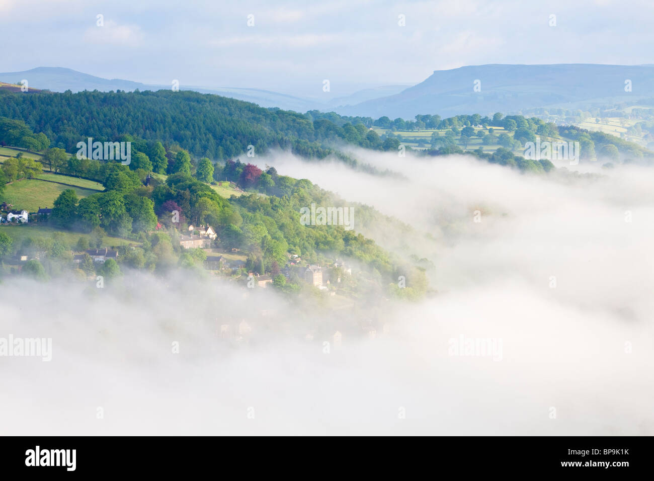 A misty Spring morning viewed from Curbar Edge looking over the mist filled valley above the village of Calver in Derbyshire Stock Photo