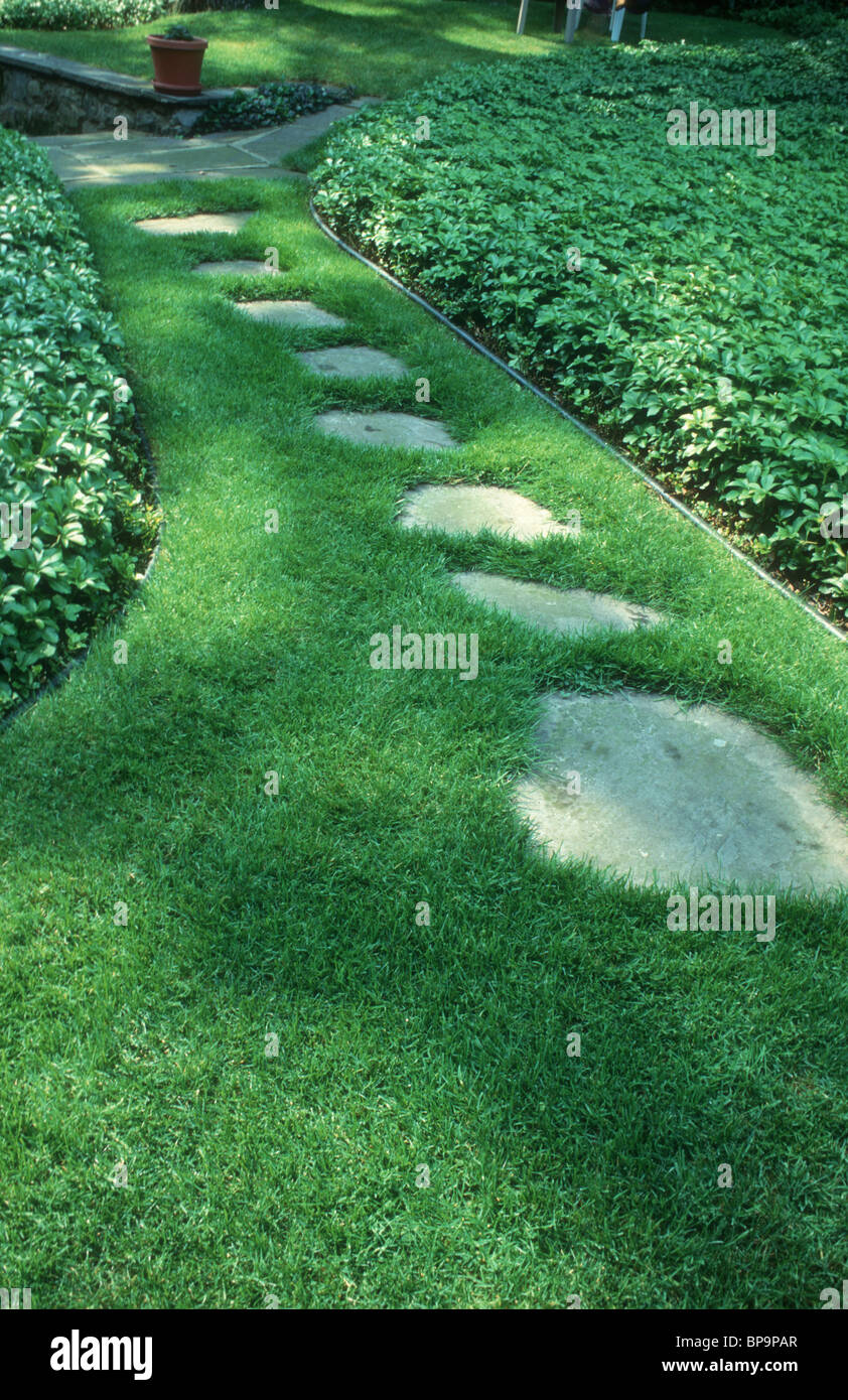 Stepping stone path in lawn in sun and shade with pachysandra evergreen ground cover, an inviting beginning of a journey Stock Photo
