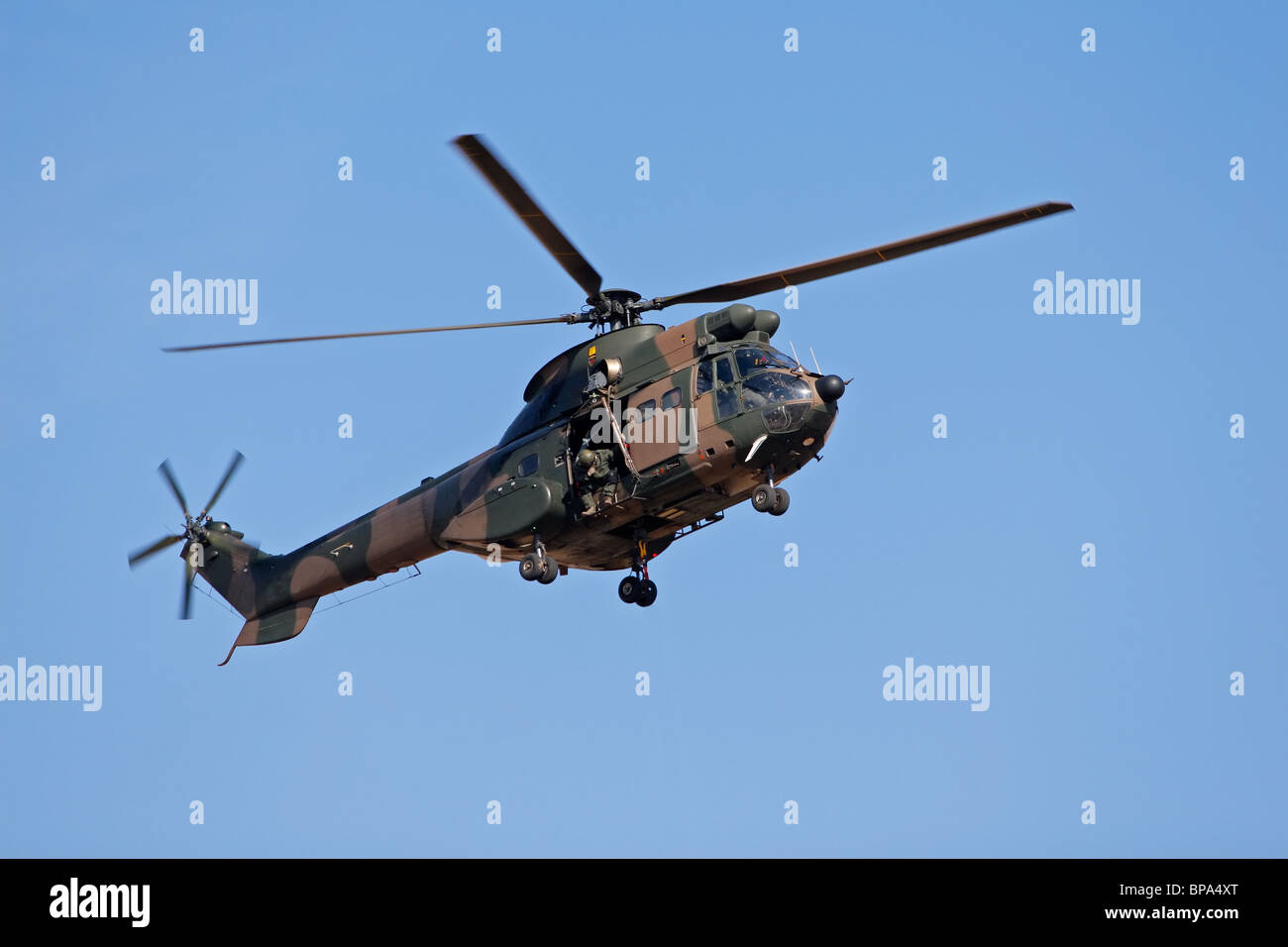 A camouflaged military helicopter in flight Stock Photo