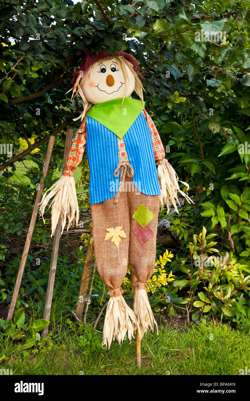 A stuffed scarecrow on a stick under a bush Stock Photo Alamy