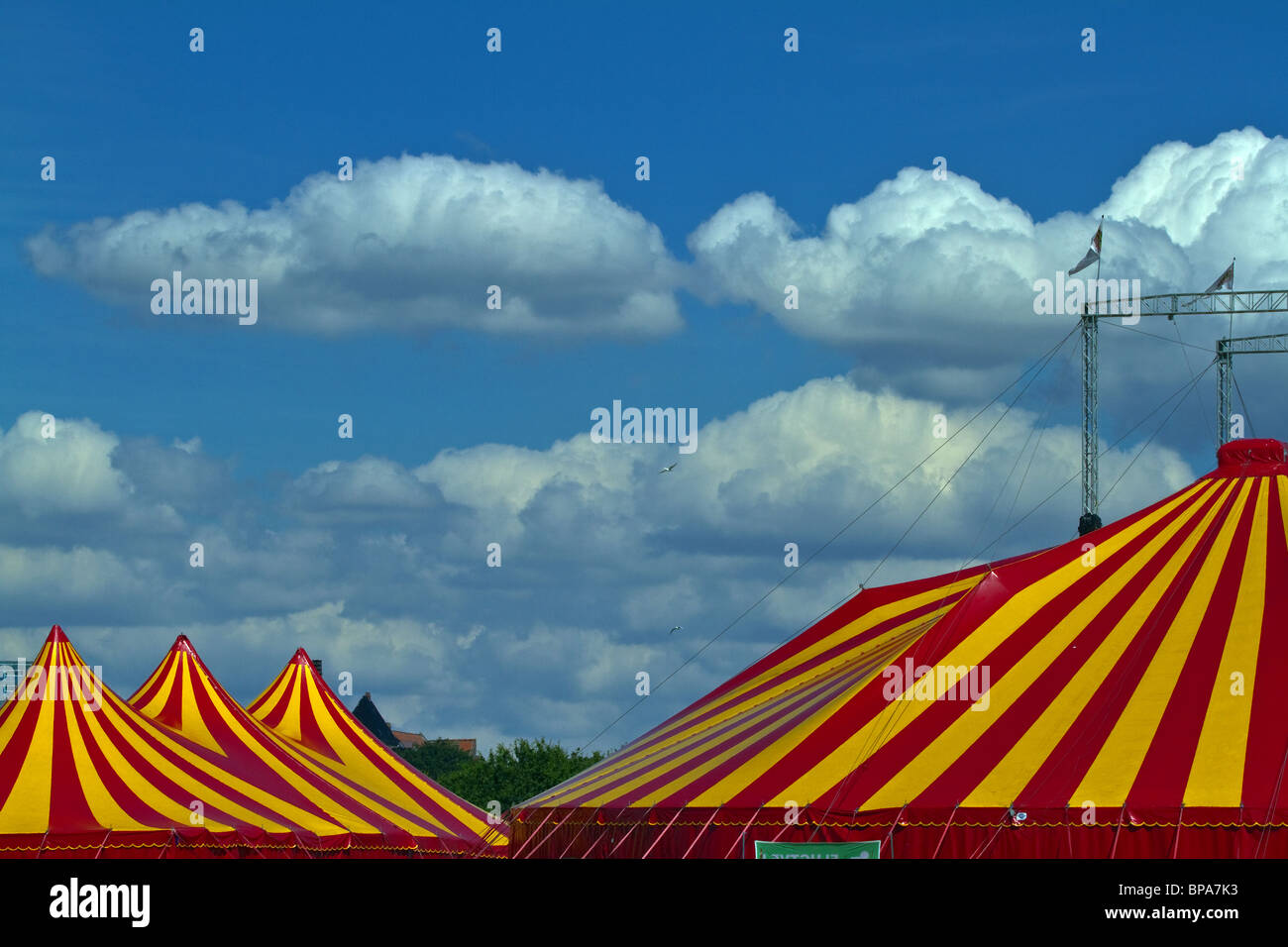 Striped circus tent against a blue sky with fluffy clouds. Horizontal Stock Photo